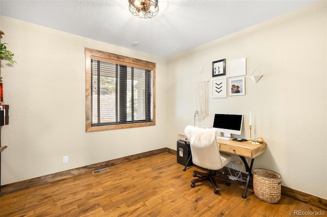 office with visible vents, baseboards, a textured ceiling, and hardwood / wood-style flooring