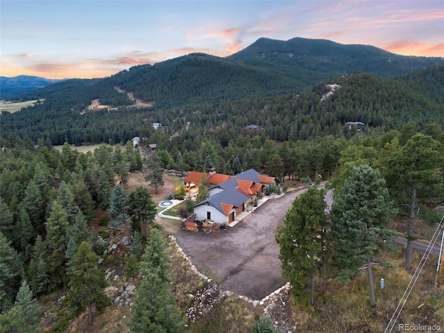 aerial view at dusk featuring a mountain view and a view of trees