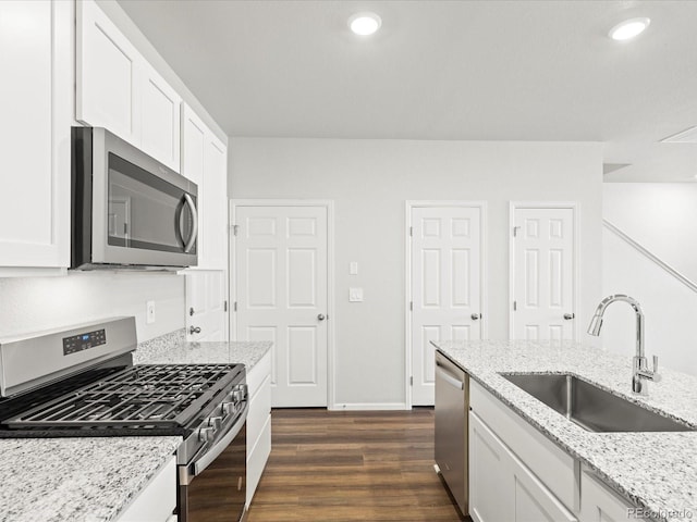 1618 Riverplace Dr Unit 2, Windsor, CO 80550 - kitchen featuring appliances with stainless steel finishes, a sink, white cabinetry, dark wood-type flooring, and light stone counters