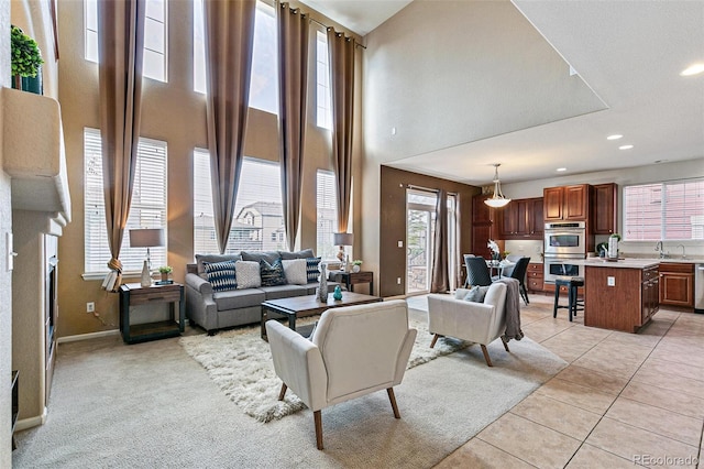 living room with a high ceiling, light tile patterned floors, and a brick fireplace