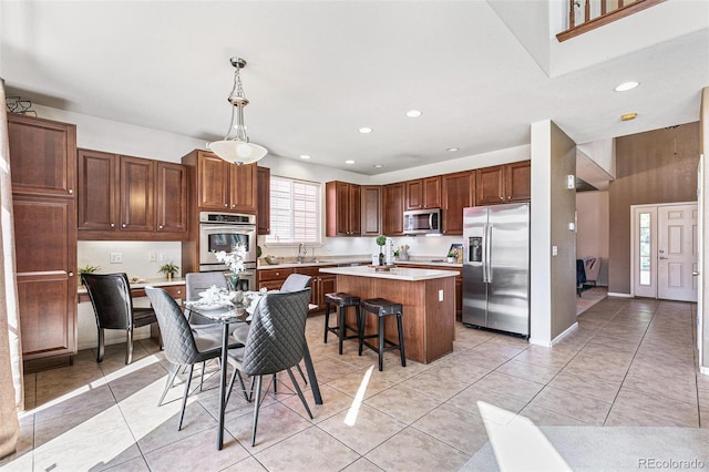 kitchen with pendant lighting, light tile patterned floors, a center island, stainless steel appliances, and sink