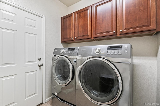 washroom featuring light tile patterned floors, cabinets, and washing machine and dryer