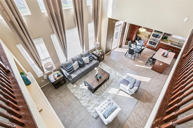 tiled living room featuring sink and a high ceiling