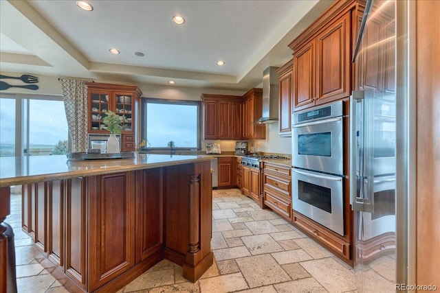 16713 W Archer Ave, Golden, CO 80401 - kitchen featuring appliances with stainless steel finishes, wall chimney range hood, a tray ceiling, a center island, and recessed lighting