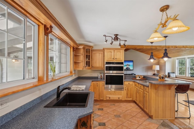 kitchen featuring stainless steel double oven, a breakfast bar area, decorative light fixtures, sink, and light tile floors