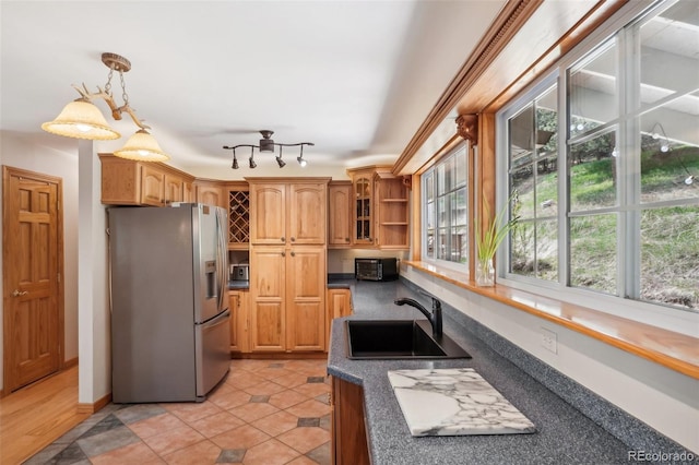 kitchen with a healthy amount of sunlight, track lighting, stainless steel fridge, and pendant lighting