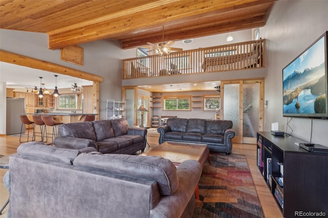 living room with beamed ceiling, ceiling fan, a healthy amount of sunlight, and wood-type flooring