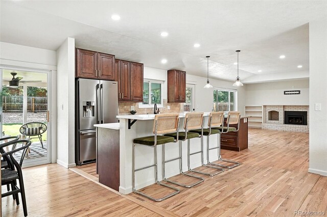 7035 S Gray Ct, Littleton, CO 80128 - kitchen featuring stainless steel refrigerator with ice dispenser, a breakfast bar, light countertops, light wood-style floors, and decorative light fixtures