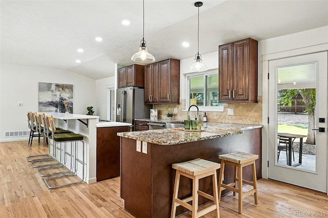 7035 S Gray Ct, Littleton, CO 80128 - kitchen with stainless steel appliances, a kitchen bar, light wood-style flooring, backsplash, and recessed lighting