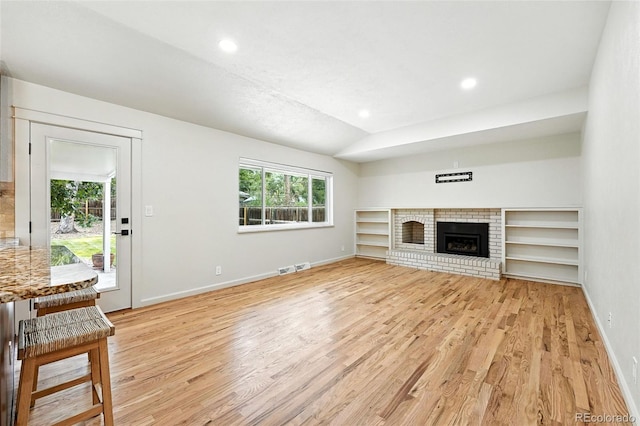7035 S Gray Ct, Littleton, CO 80128 - unfurnished living room with light wood-style floors, recessed lighting, and a brick fireplace