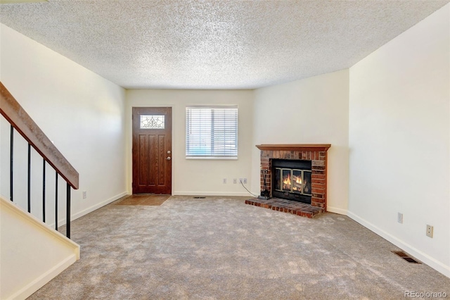 unfurnished living room featuring carpet, a textured ceiling, and a brick fireplace