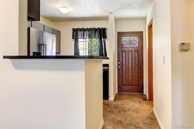 interior space featuring kitchen peninsula, a textured ceiling, and high end fridge