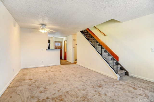 unfurnished living room featuring carpet, ceiling fan, and a textured ceiling