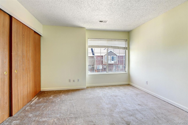 unfurnished bedroom featuring light carpet, a closet, and a textured ceiling