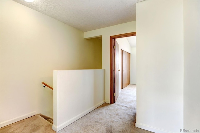 hall featuring carpet flooring and a textured ceiling