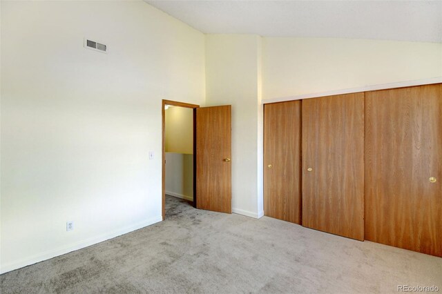 unfurnished bedroom featuring a closet, high vaulted ceiling, and light colored carpet