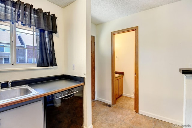 kitchen with dishwasher, a textured ceiling, and sink