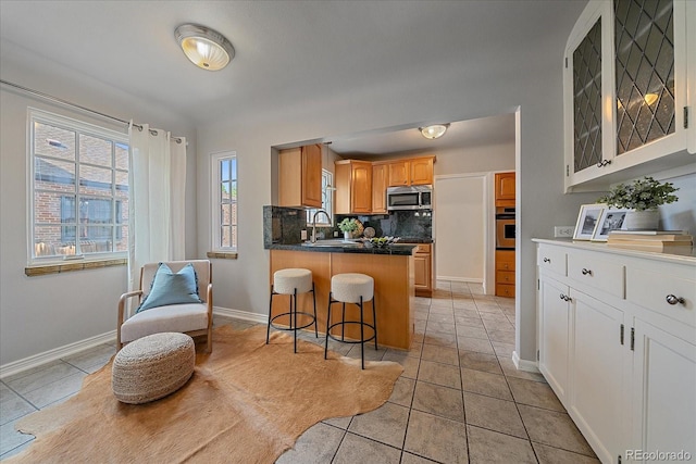2065 Leyden St, Denver, CO 80207 - kitchen featuring stainless steel appliances, glass insert cabinets, a kitchen bar, a peninsula, and light tile patterned flooring