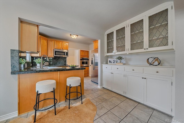 2065 Leyden St, Denver, CO 80207 - kitchen featuring stainless steel appliances, glass insert cabinets, a peninsula, light tile patterned floors, and a breakfast bar