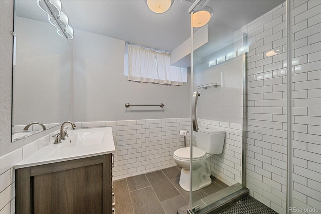 2065 Leyden St, Denver, CO 80207 - full bathroom with tile walls, toilet, vanity, a stall shower, and wainscoting