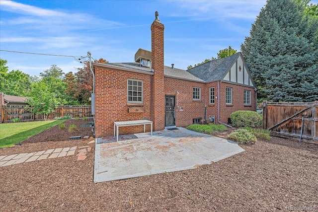 2065 Leyden St, Denver, CO 80207 - rear view of house featuring brick siding, a chimney, a fenced backyard, and a patio area