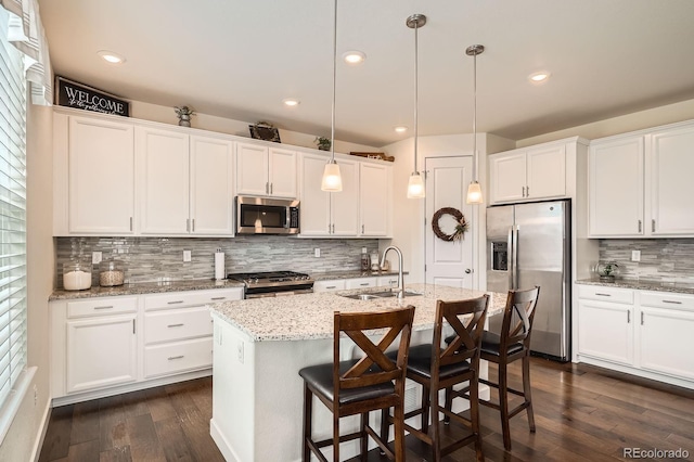 16043 Fillmore St, Thornton, CO 80602 - kitchen with stainless steel appliances, tasteful backsplash, dark wood-style floors, white cabinets, and an island with sink