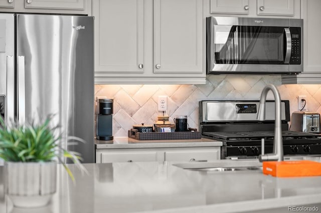 kitchen featuring decorative backsplash, appliances with stainless steel finishes, and white cabinets