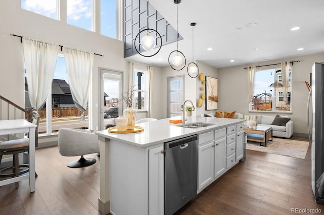 kitchen with a kitchen island with sink, white cabinets, hanging light fixtures, sink, and stainless steel appliances