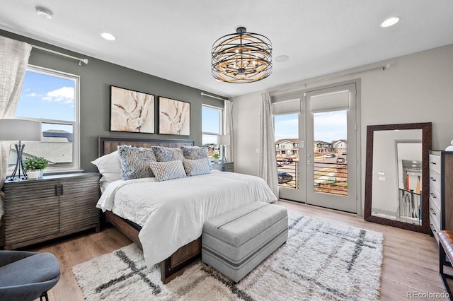 bedroom with a notable chandelier, access to exterior, and light hardwood / wood-style flooring