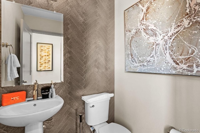 bathroom with decorative backsplash, toilet, and sink