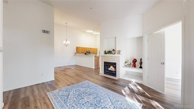 living room featuring hardwood / wood-style floors, a tiled fireplace, and an inviting chandelier