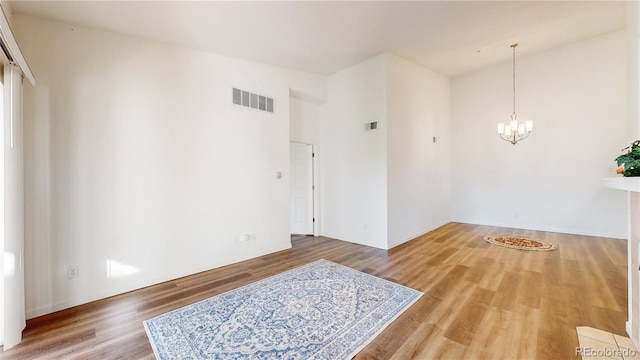 empty room featuring hardwood / wood-style flooring and a chandelier