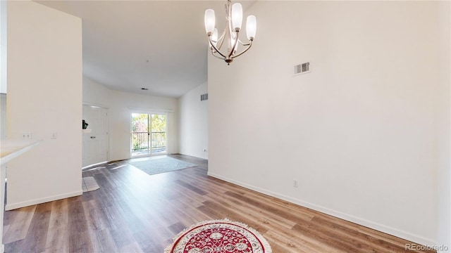 interior space with hardwood / wood-style floors, vaulted ceiling, and a chandelier