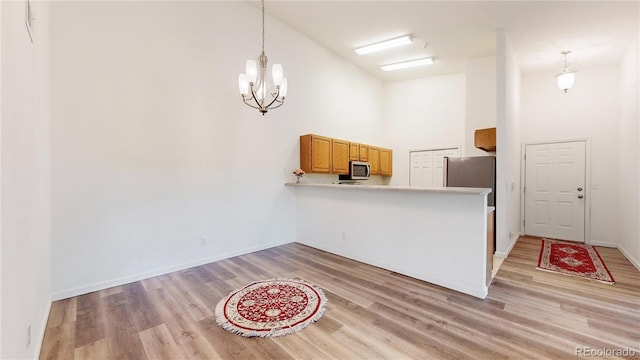 kitchen with a towering ceiling, appliances with stainless steel finishes, and light hardwood / wood-style floors