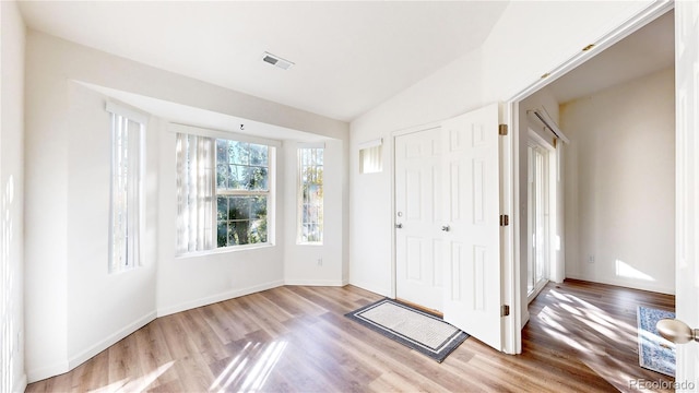 foyer entrance with light hardwood / wood-style flooring and lofted ceiling