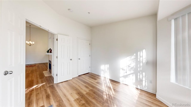 unfurnished bedroom featuring a chandelier and wood-type flooring