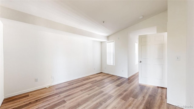 unfurnished room with lofted ceiling and light wood-type flooring