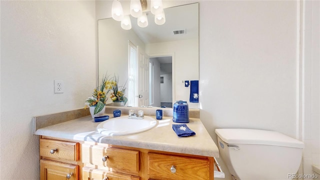 bathroom with vanity, an inviting chandelier, and toilet