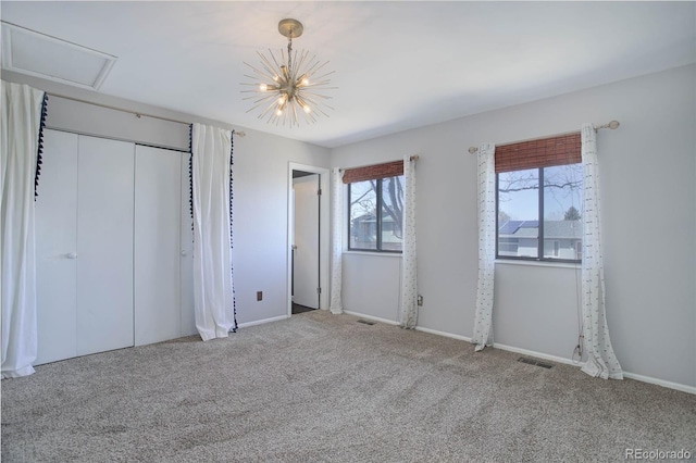 unfurnished bedroom featuring an inviting chandelier, carpet floors, and a closet