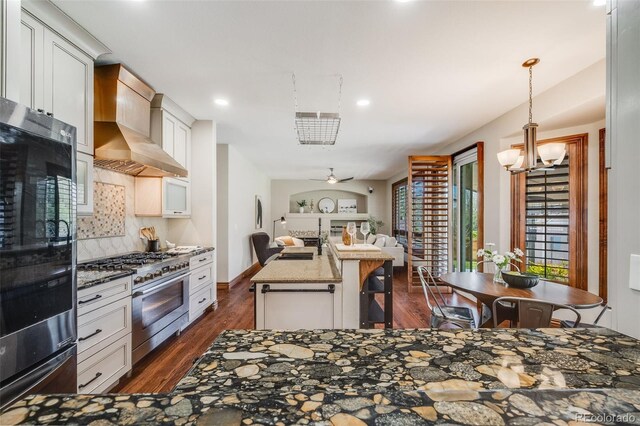 17522 E Dewberry Dr, Parker, CO 80134 - kitchen featuring stainless steel stove, wall chimney exhaust hood, open floor plan, fridge, and dark wood finished floors