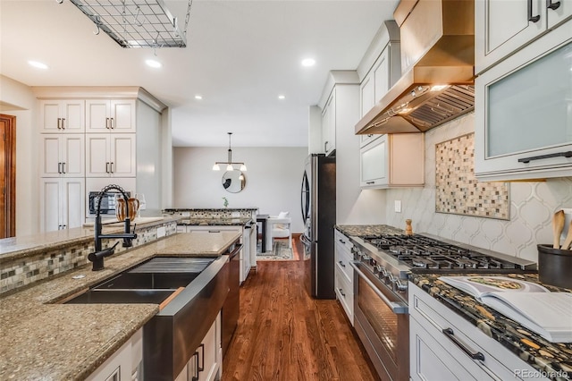 17522 E Dewberry Dr, Parker, CO 80134 - kitchen featuring appliances with stainless steel finishes, wall chimney range hood, a sink, dark stone counters, and tasteful backsplash