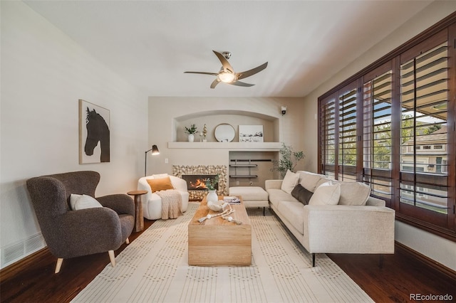 17522 E Dewberry Dr, Parker, CO 80134 - living area featuring ceiling fan, wood finished floors, a warm lit fireplace, and baseboards
