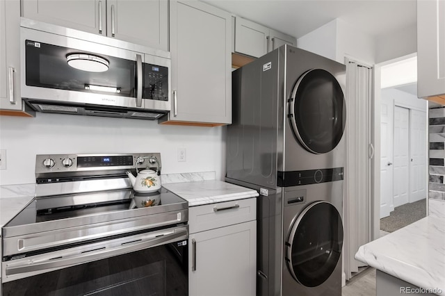 4728 Dover St, Wheat Ridge, CO 80033 - kitchen with stainless steel appliances, stacked washer / dryer, and light stone counters