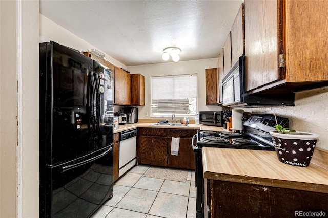 kitchen with sink, black appliances, and light tile patterned floors