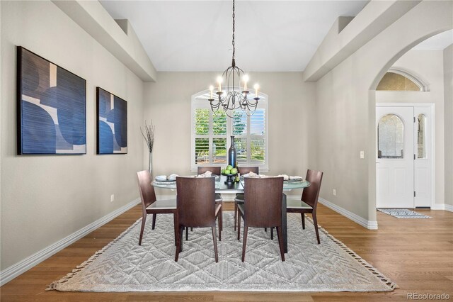 3485 Park Ridge Rd, Sedalia, CO 80135 - dining area featuring a chandelier, wood finished floors, arched walkways, and baseboards