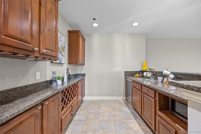 3485 Park Ridge Rd, Sedalia, CO 80135 - kitchen with stainless steel microwave, dark stone counters, a sink, baseboards, and brown cabinets