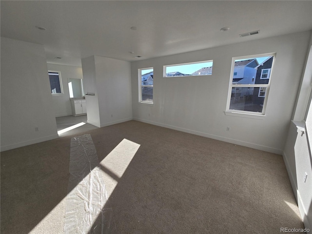 empty room with baseboards, visible vents, and carpet flooring