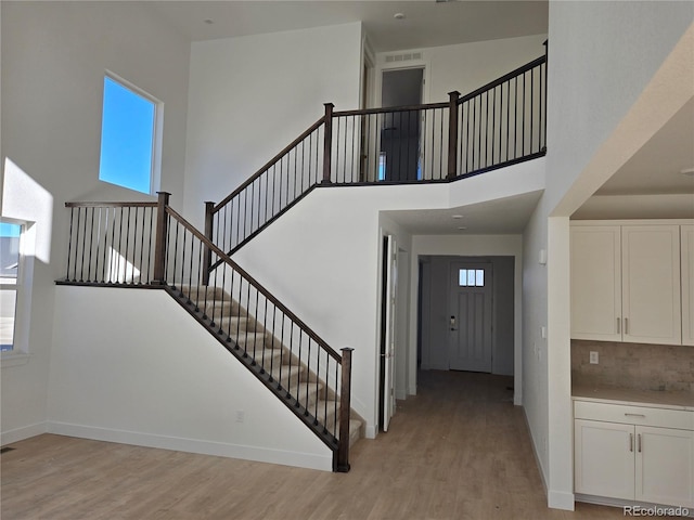 staircase featuring a high ceiling, baseboards, and wood finished floors