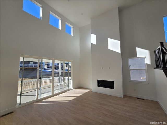 unfurnished living room with baseboards, a fireplace, visible vents, and wood finished floors