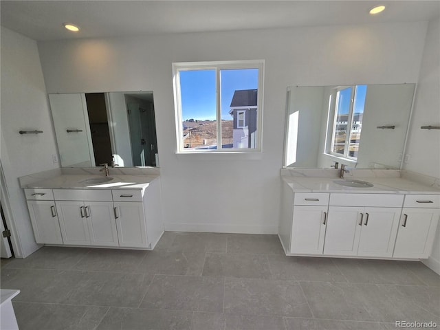 bathroom with two vanities, a sink, and baseboards